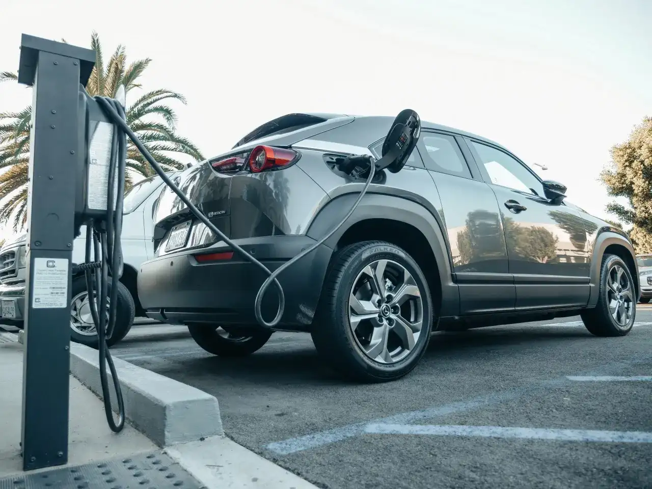Szary samochód typu SUV z wtyczką ładowania podłączoną do portu. To przykład technologii mild hybrid, która wspomaga silnik spalinowy.