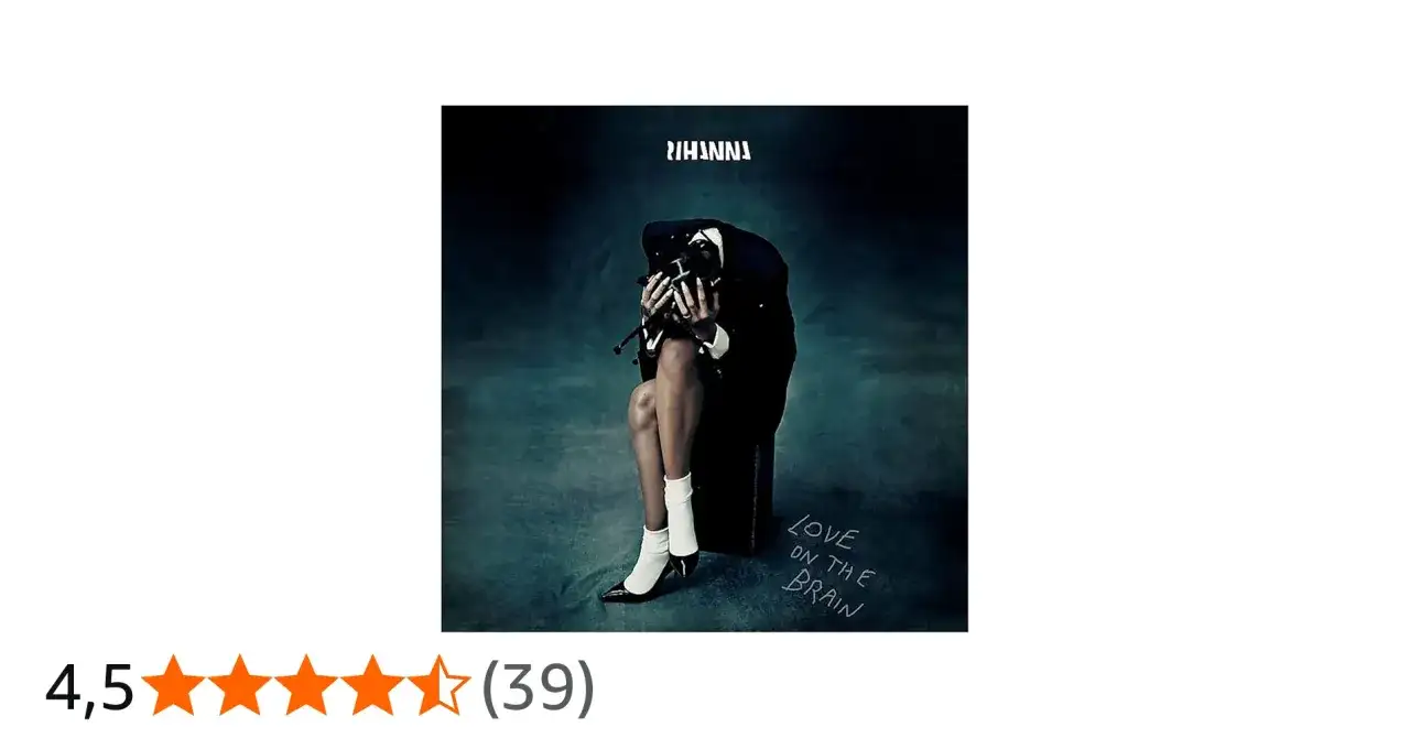 Rihanna w czarnym garniturze, siedząca z głową opuszczoną na dłonie, na tle mrocznego gradientu.