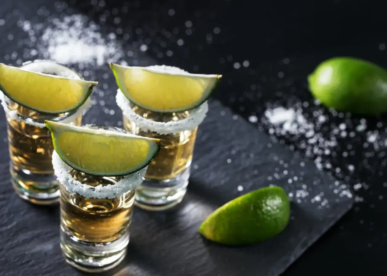 Trzy kieliszki tequili z solą i limonką, gotowe do degustacji. Oto jak pić tequilę, by poczuć jej smak.