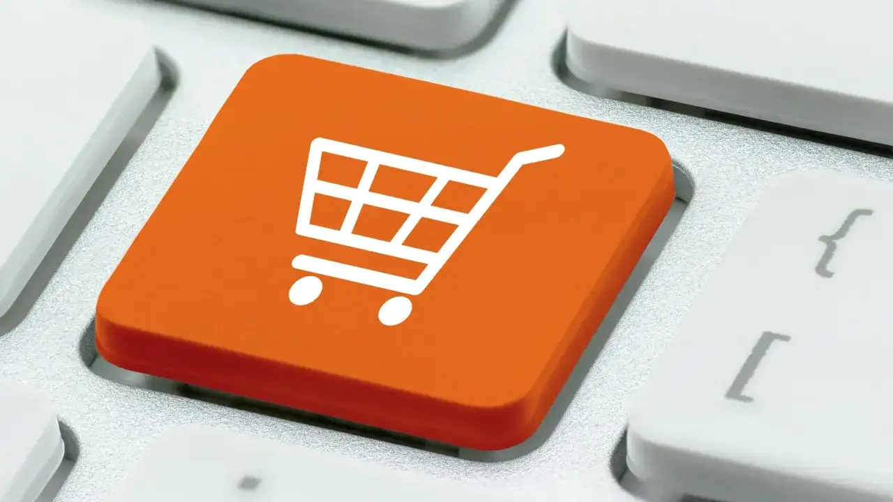 Pomarańczowy klawisz z ikoną koszyka na zakupy. To symbol e-commerce co to jest, czyli handlu elektronicznego.