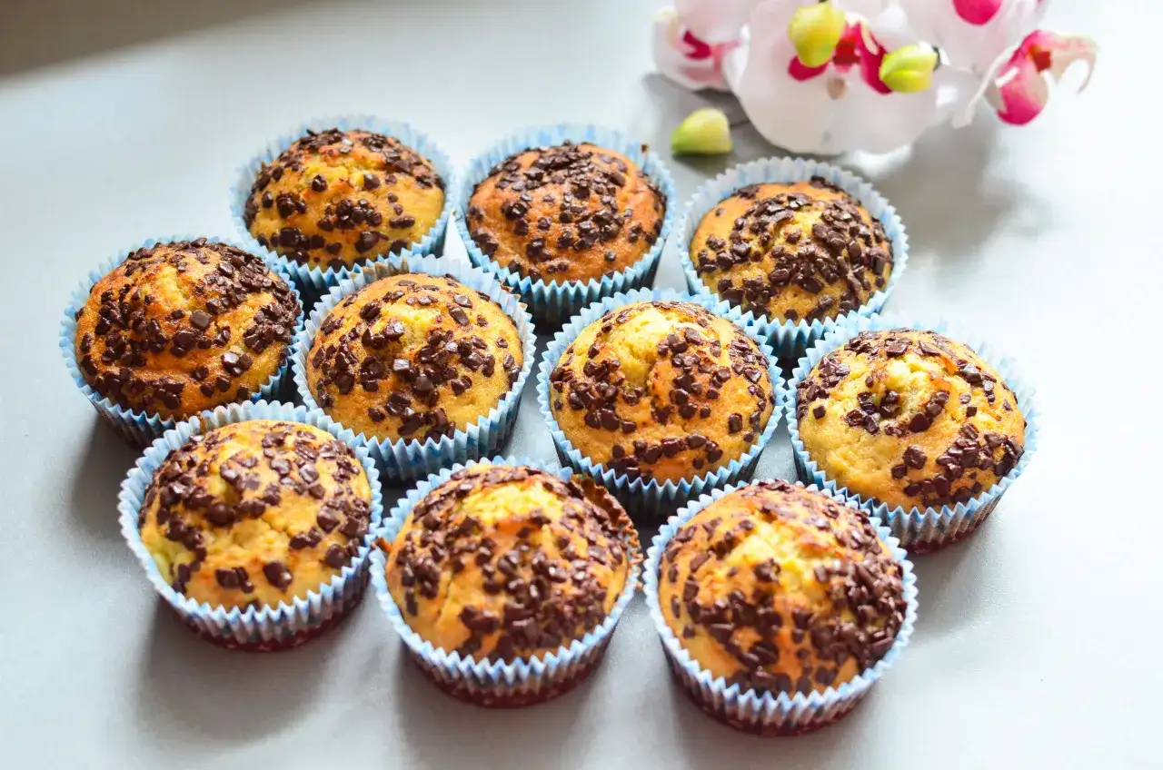 Urocze muffinki bananowe z czekoladą, posypane obficie czekoladowymi drobinkami, wyglądają apetycznie.