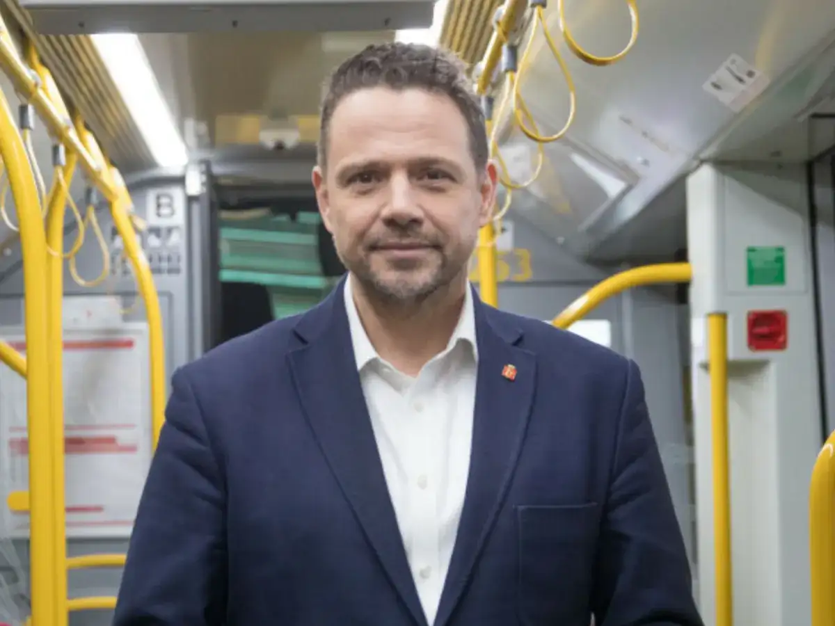 Rafał Trzaskowski, prezydent Warszawy, w środkach komunikacji miejskiej. Jego życiorys to historia zaangażowania w rozwój stolicy.