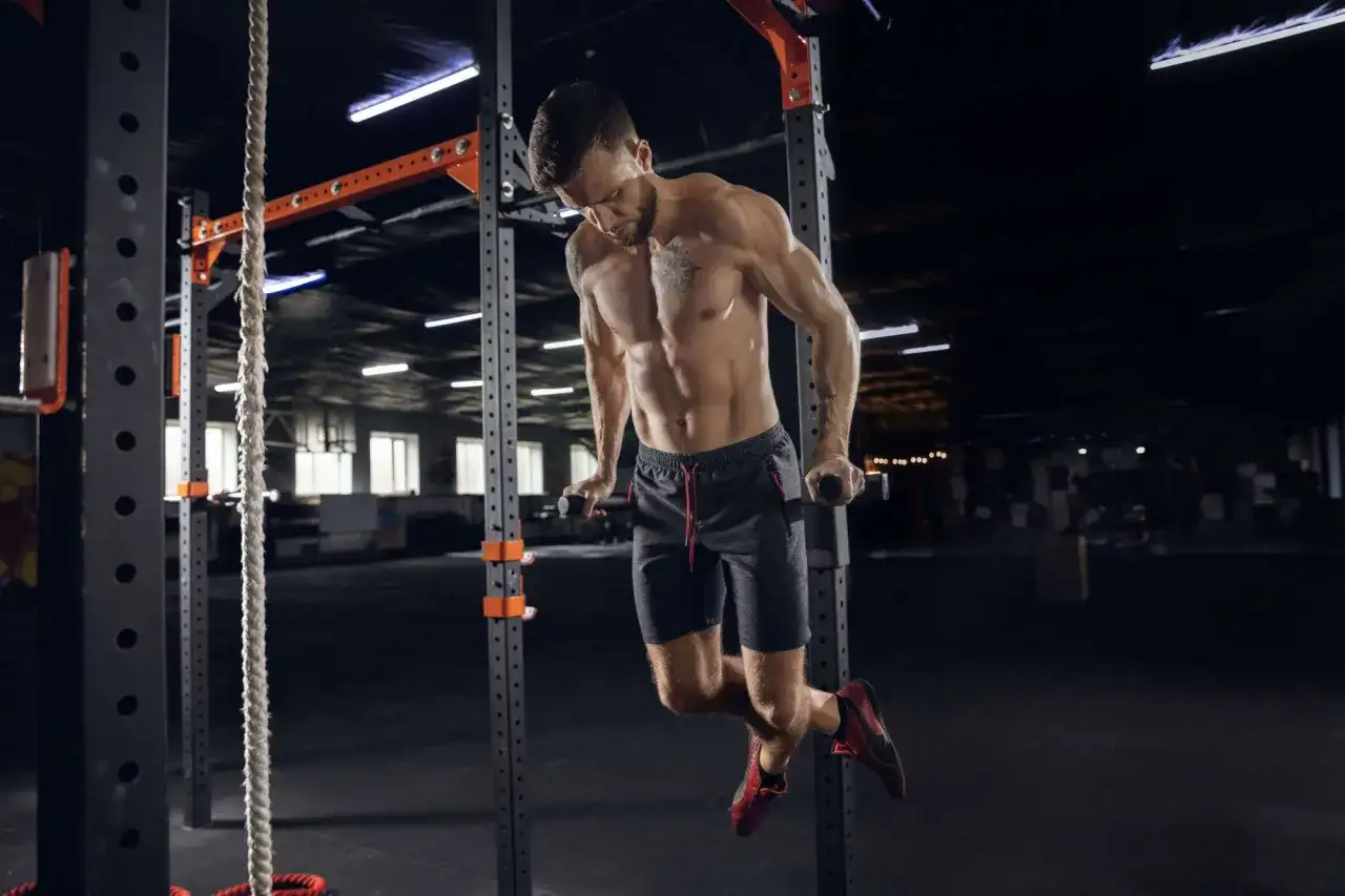 Mężczyzna wykonuje pompki na poręczach w siłowni CrossFit.