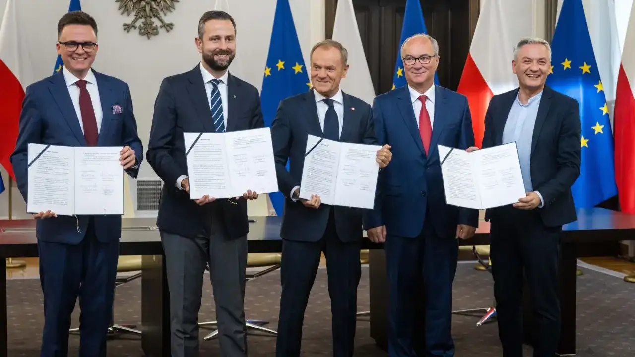 Pięciu polityków prezentuje dokumenty. Ich uśmiechy sugerują sukces, być może związany z tym, ile posłów ma koalicja rządząca.