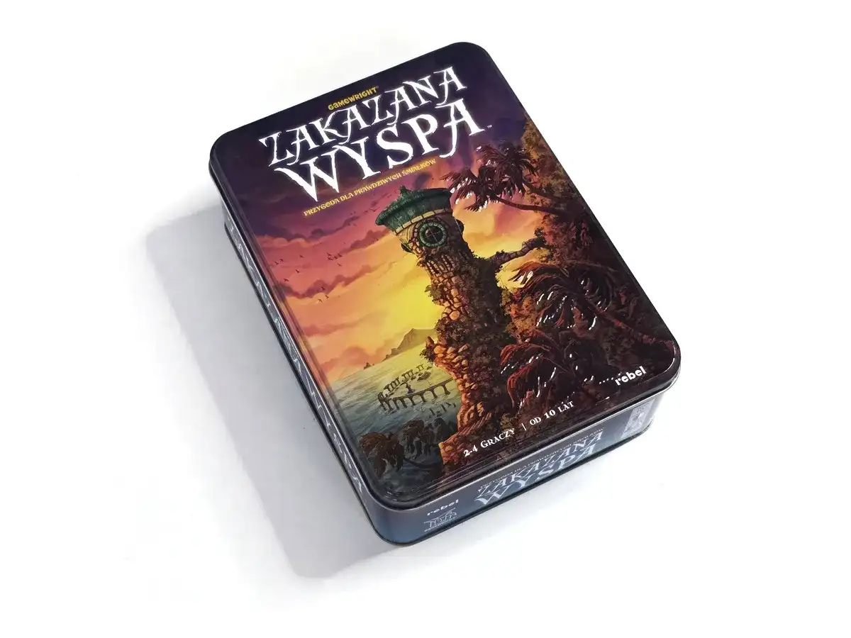 Metalowe pudełko gry planszowej "Zakazana Wyspa" z ilustracją wieży na klifie i palm.