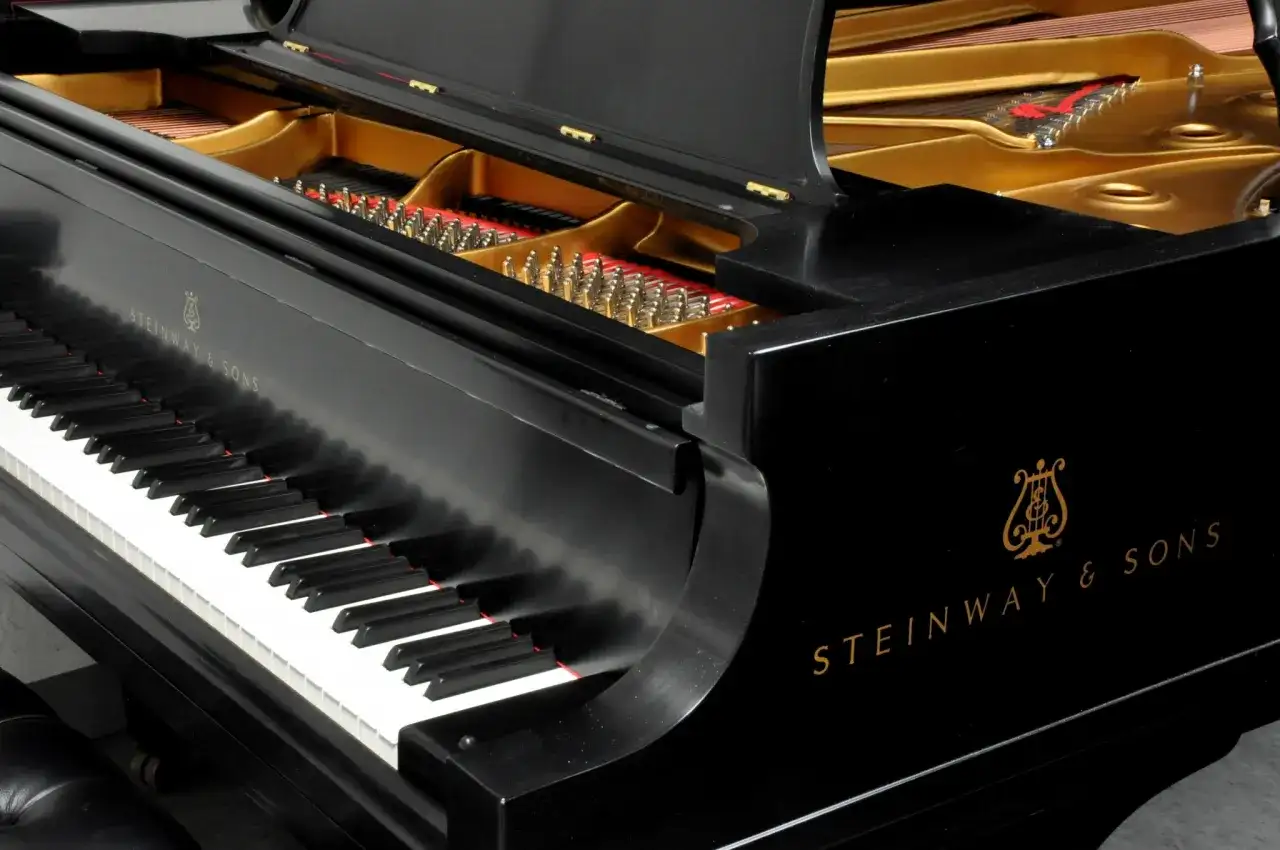 Czarne pianino Steinway & Sons z otwartą klapą, ukazującą struny i złote wnętrze. Zastanawiasz się, ile waży płyta mosiężna w pianinie?