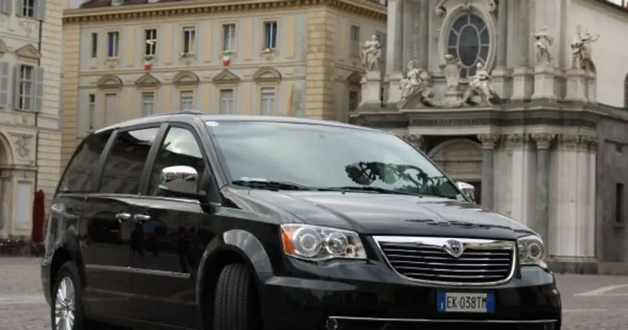 Czarny Lancia Voyager na tle zabytkowej architektury.