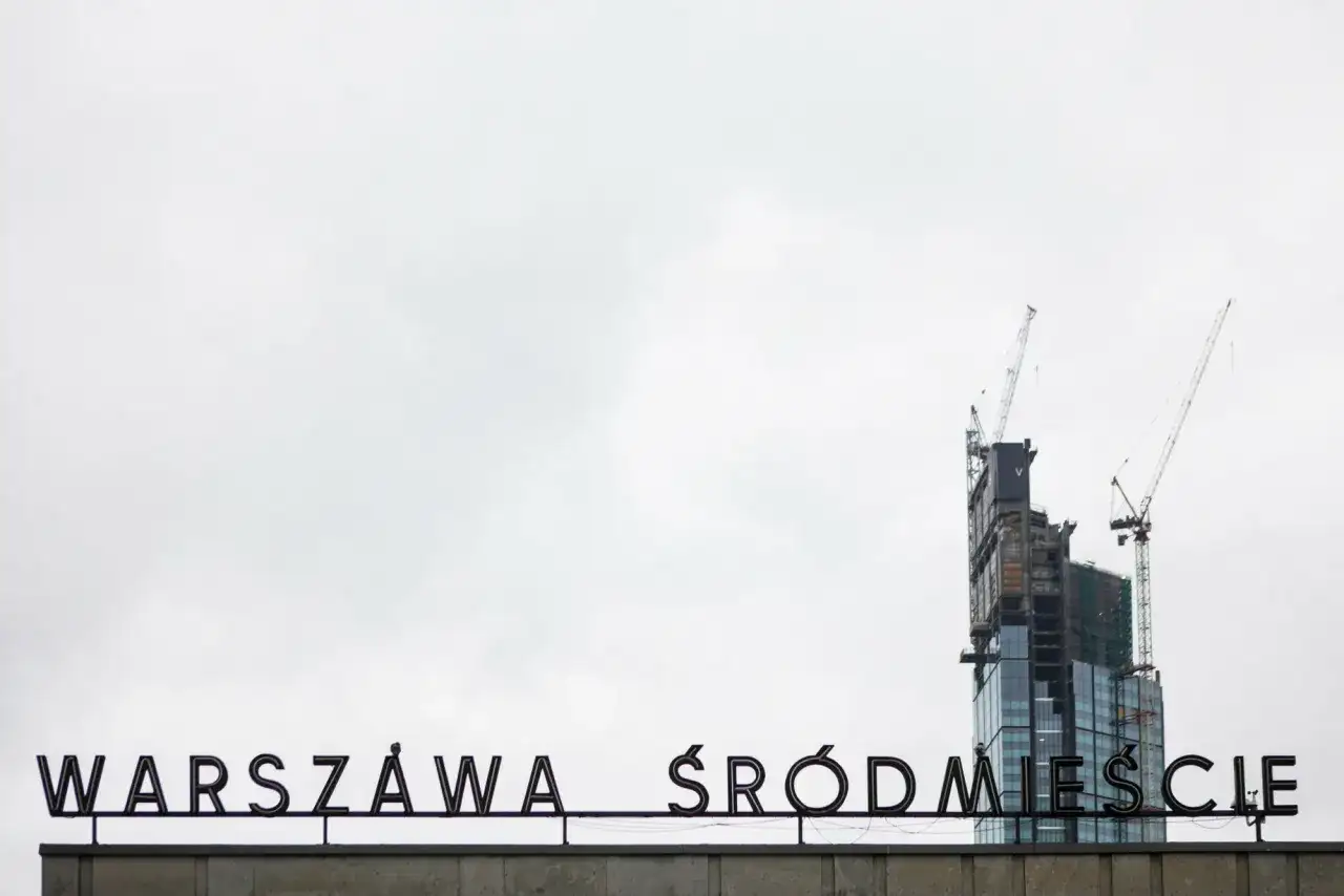 Varso Tower w budowie z dźwigami, na tle napisu "WARSZAWA ŚRÓDMIEŚCIE".