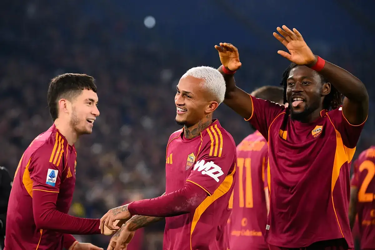 Piłkarze AS Roma świętują zwycięstwo nad Genoą CFC. Radość na twarzach zawodników, jeden z nich podnosi ręce w geście triumfu.