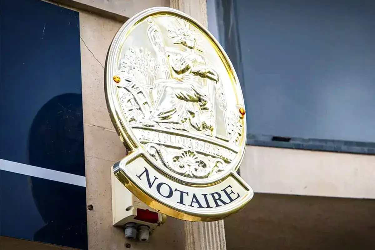 Plaque dorée "NOTAIRE" sur un mur. Une image qui pourrait évoquer un détournement d'héritage par notaire, une affaire sombre.