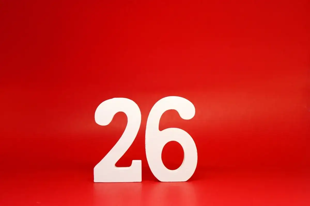 Białe cyfry 26 na czerwonym tle. Tyle dni urlopu zostało do wymarzonej podróży!