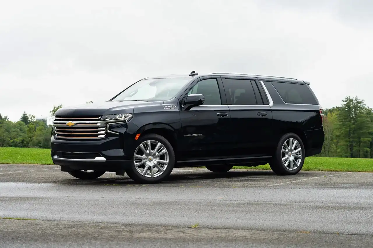 Czarny Chevrolet Suburban High Country z chromowanymi felgami stoi na parkingu.