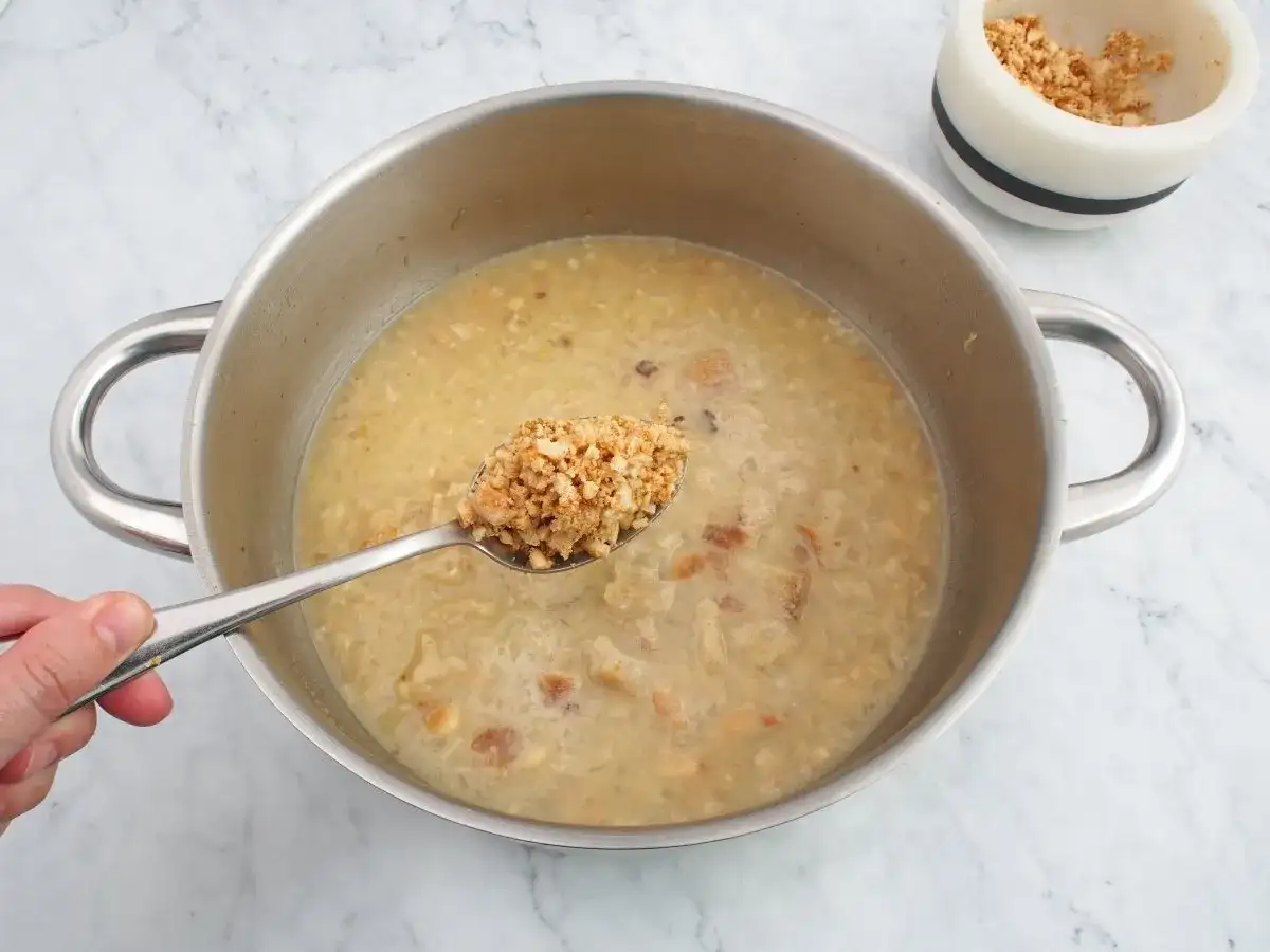 Cuchara con trozos de almendras listas para añadir a la olla, creando una deliciosa salsa de almendras.