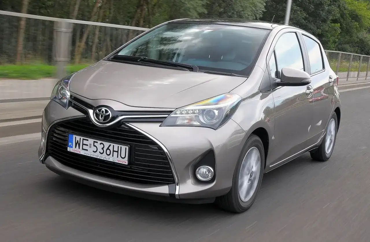 Szary Toyota Yaris w ruchu drogowym, widok z przodu.