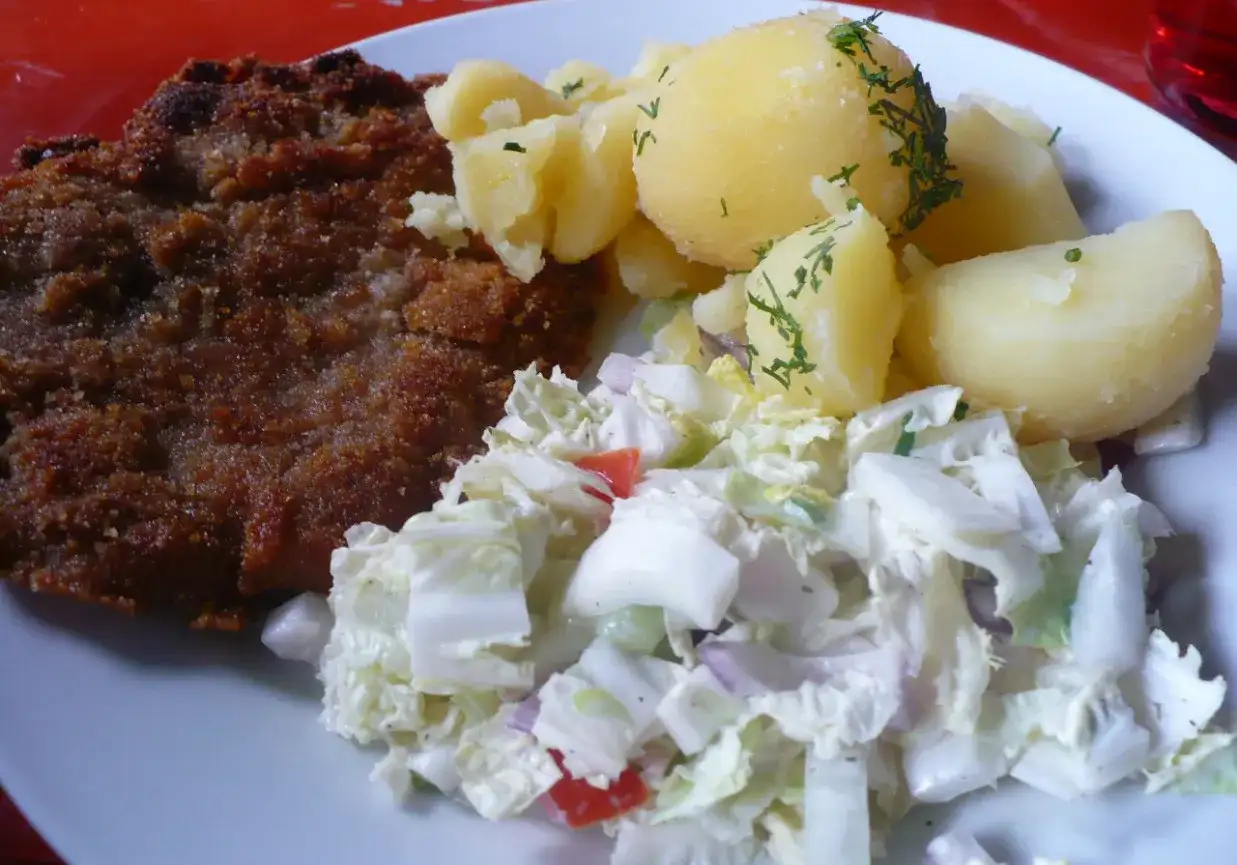 Kotlet schabowy z ziemniakami i surówką z białej kapusty.