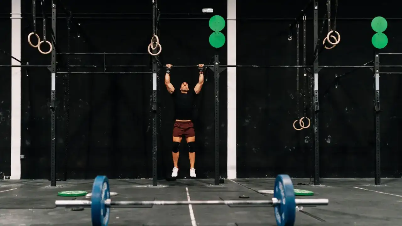 Mężczyzna wykonuje podciąganie na drążku w siłowni CrossFit.