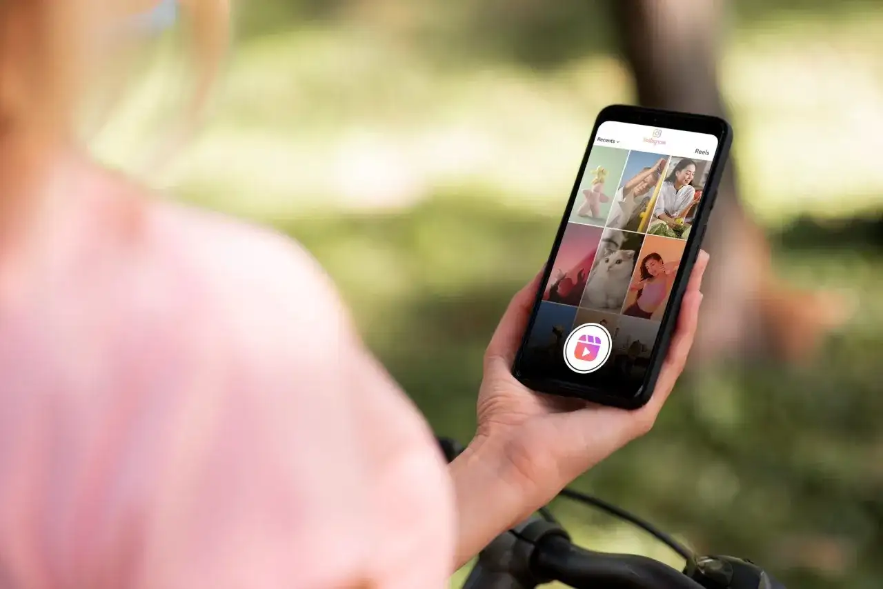 Osoba trzyma smartfon z widokiem na ekran Instagram Reels z różnymi zdjęciami.