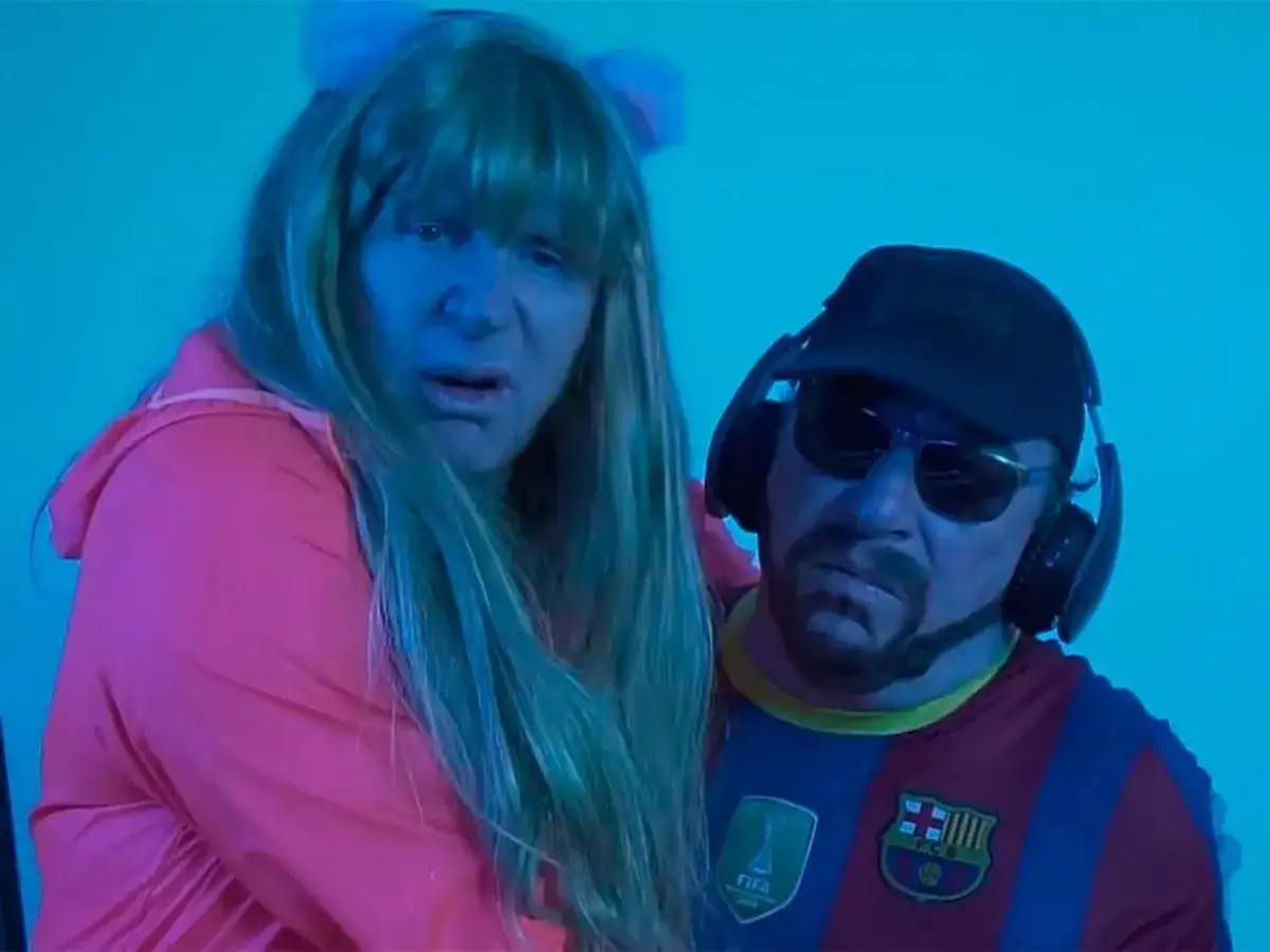 Dos personas con peluca y gorra, una con camiseta del Barça, parecen estar cantando la letra de "el pantalon".