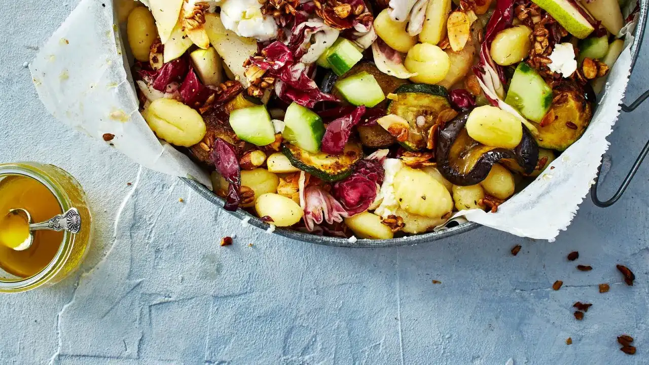 Ein köstlicher lauwarmer Gnocchi-Salat mit gegrilltem Gemüse, Radicchio, Birne und Nüssen, serviert mit Honig.