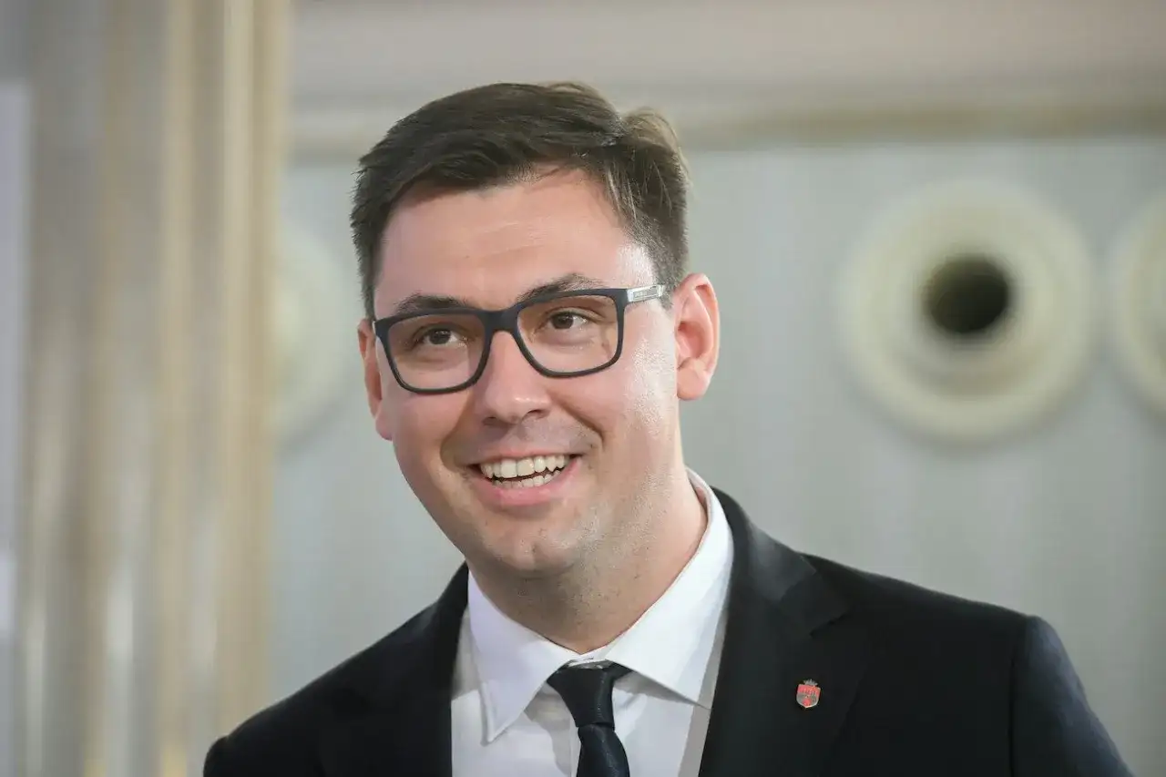 Uśmiechnięty Konrad Frysztak w okularach, w garniturze. Jego wykształcenie pozwala mu na pewność siebie w każdej sytuacji.