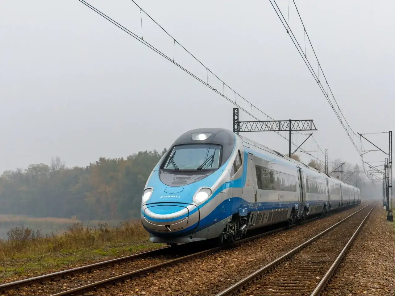 Pendolino pędzi po torach, łącząc Kraków z Warszawą. Pociąg PKP Intercity wjeżdża w mglisty krajobraz.