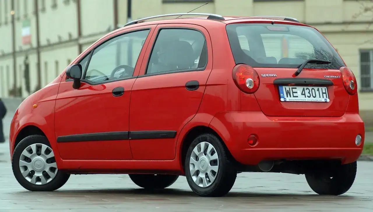 Czerwony Chevrolet Matiz, model Spark, zaparkowany na ulicy.