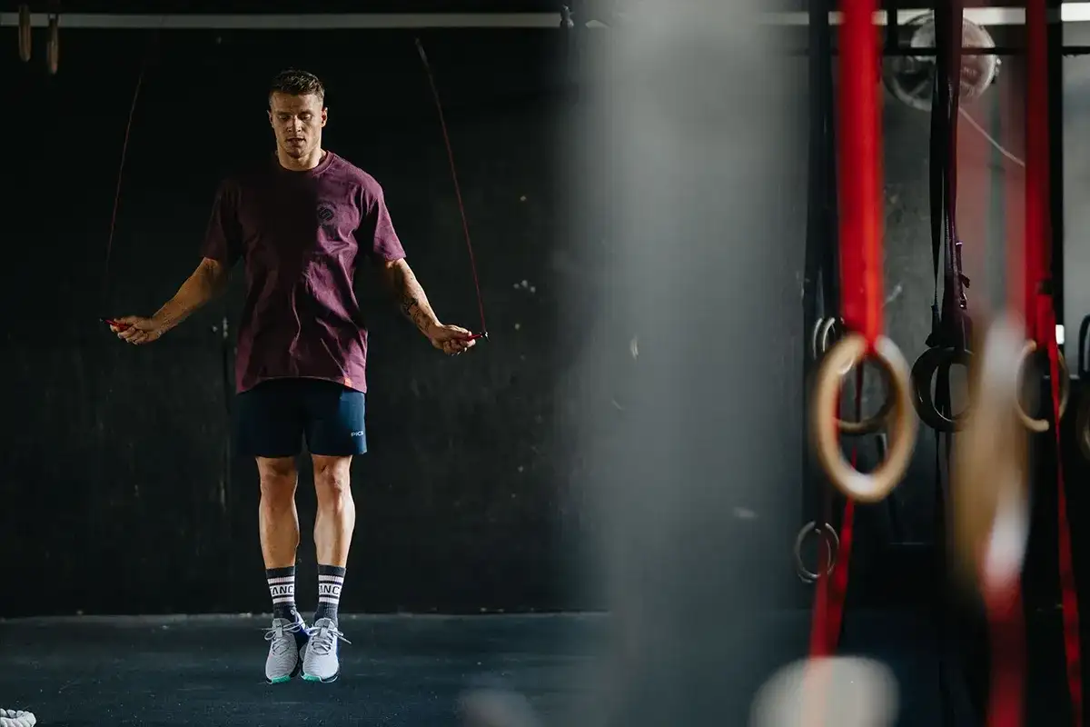 Mężczyzna w sportowym stroju skacze na skakance w siłowni.