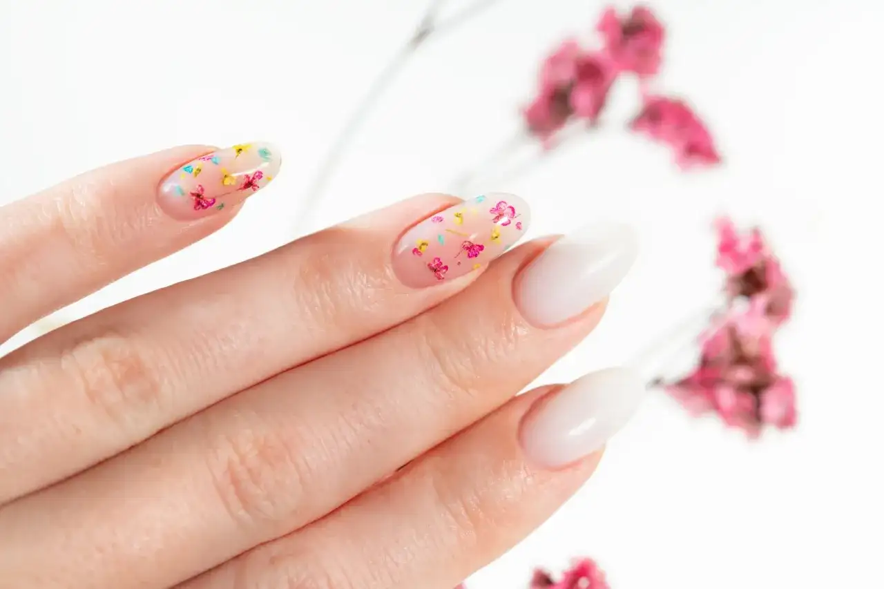 Delikatne, przezroczyste paznokcie z zatopionymi suszonymi kwiatami. Uroczy manicure w wiosennym stylu.