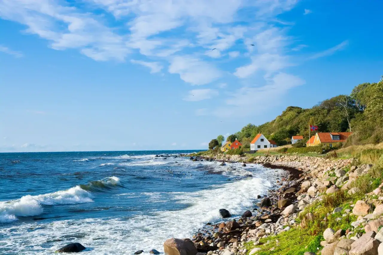Malownicze domki na wzgórzu, duńska wyspa na Bałtyku, falujące morze i kamienista plaża.