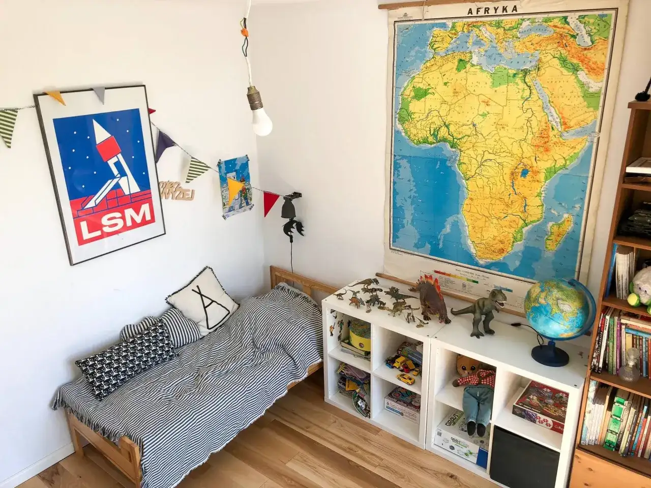 Pokój dziecka po metamorfozie: łóżko w paski, dinozaury i mapa Afryki.