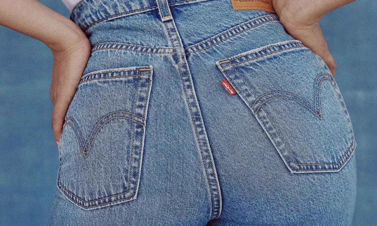Zbliżenie na tył dżinsowych spodni z widocznymi kieszeniami i czerwoną metką Levi's.