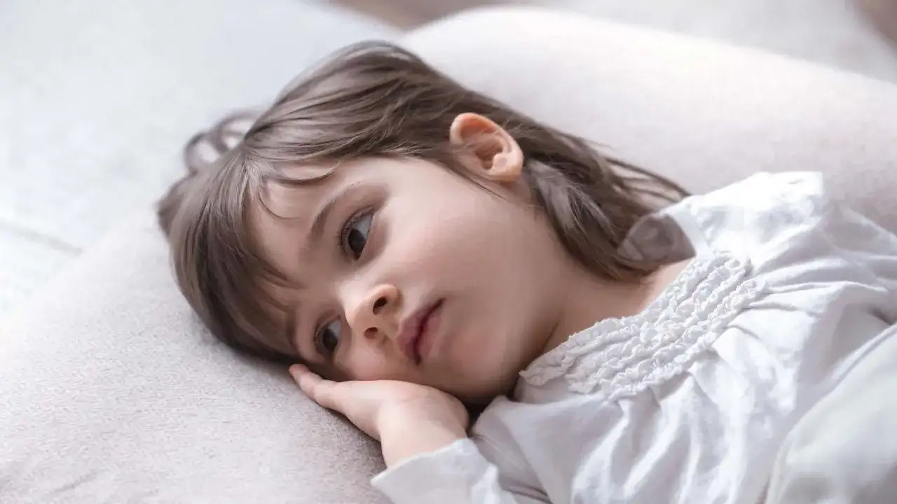 Smutna dziewczynka, 1,5 roczne dziecko, leży na poduszce, nie chce spać, zamyślona.