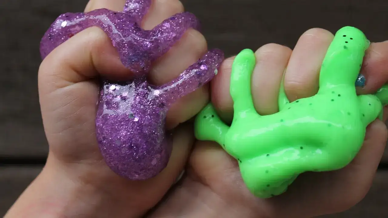 Dzieci bawią się fioletowym i zielonym slime'em, pokazując, jak zrobić slime.