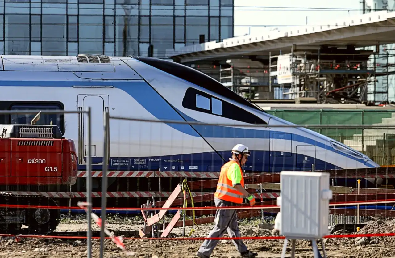 Budowa stacji, pracownik w kamizelce odblaskowej przechodzi obok pociągu Pendolino. Ile jedzie pociąg z Krakowa do Kołobrzegu?
