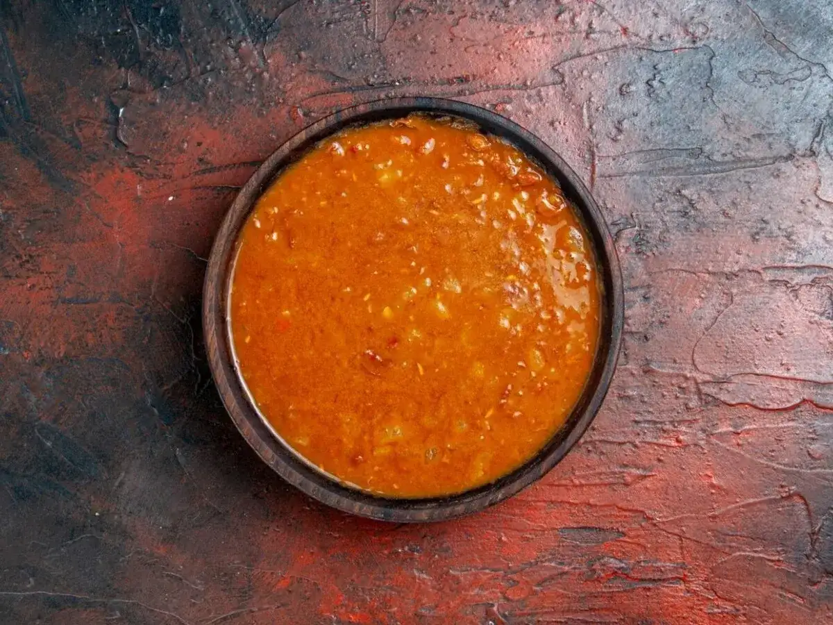 Un tazón de salsa emmy que lleva, con trozos de tomate y especias, sobre una superficie rústica.