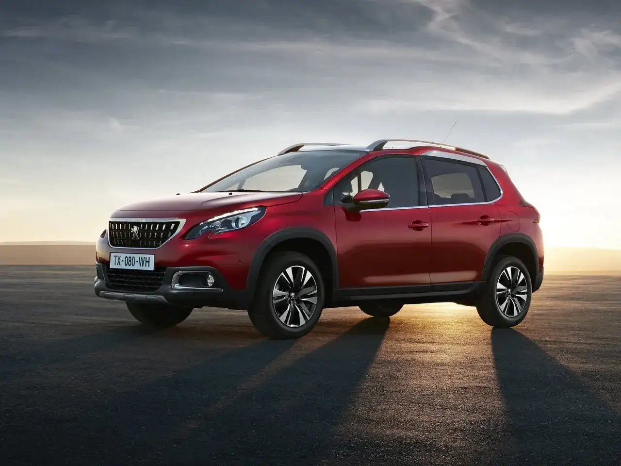Czerwony Peugeot 2008 na tle zachodzącego słońca. Wiele osób szuka peugeot 2008 opinie przed zakupem.