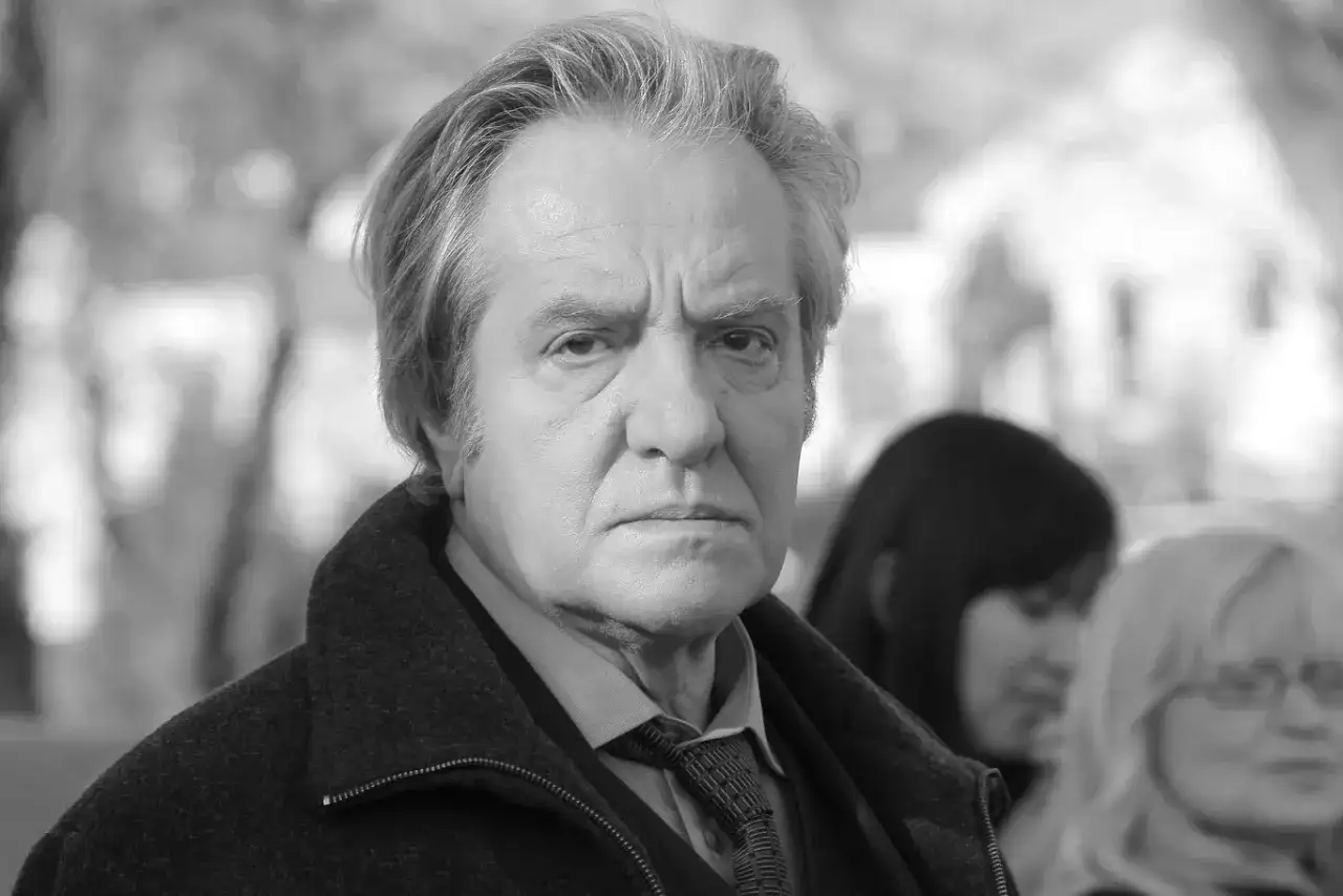 Jerzy Grałek, aktor, w czarnym płaszczu i krawacie, zamyślony.