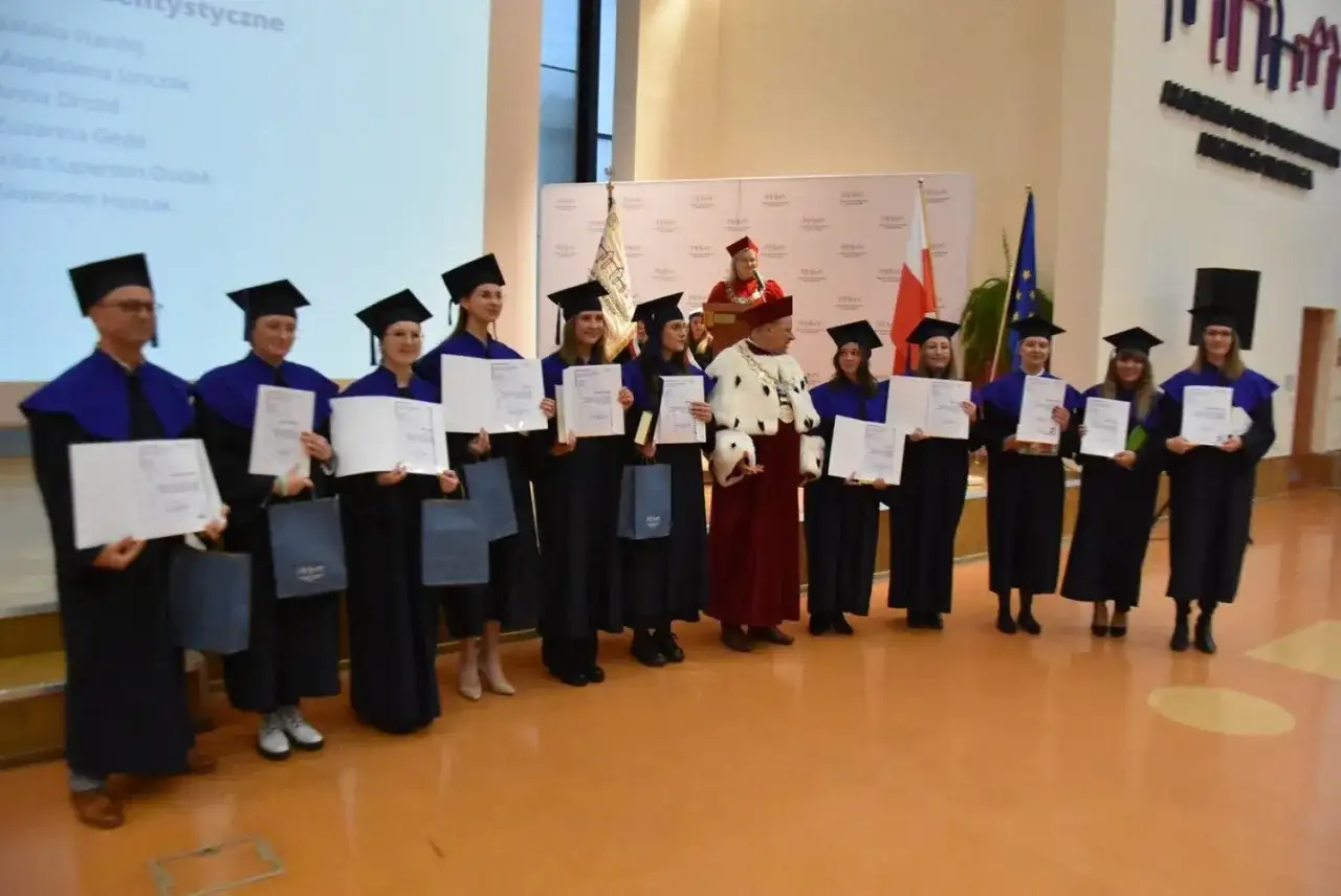 Absolwenci w togach i biretach odbierają dyplomy. Uroczystość wręczenia tytułów licencjat.