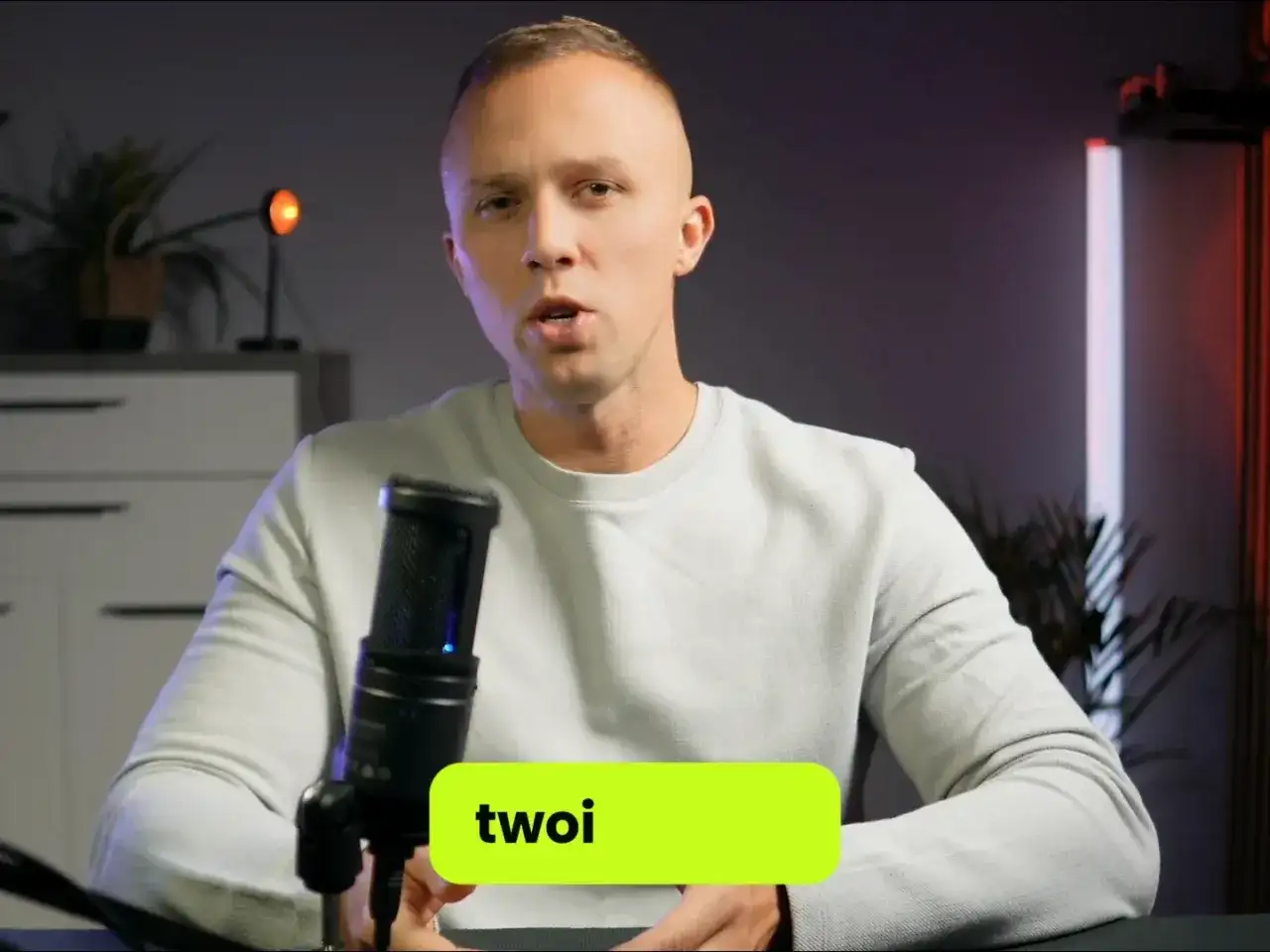 Mężczyzna przy mikrofonie opowiada o skutecznym SEO. Zielony napis "twoi" sugeruje, że chodzi o Twoje SEO.