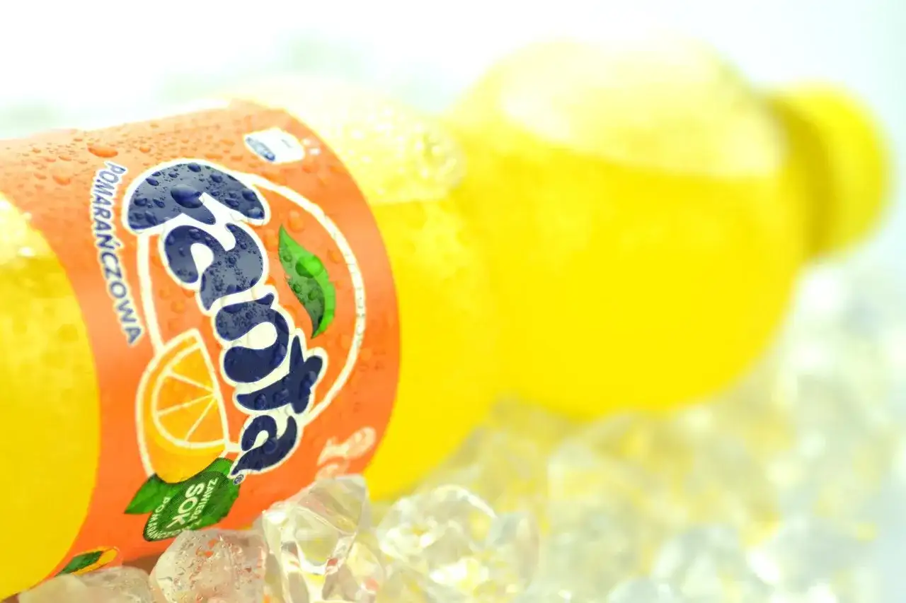 Butelka Fanta Pomarańczowa z sokiem z pomarańczy na lodzie.