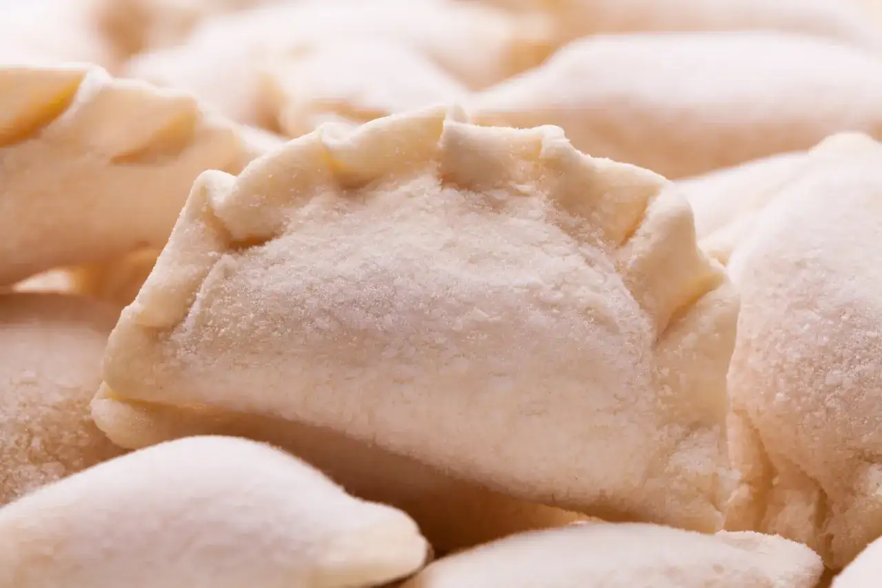 Zamrożone pierogi ułożone blisko siebie, pokryte szronem.