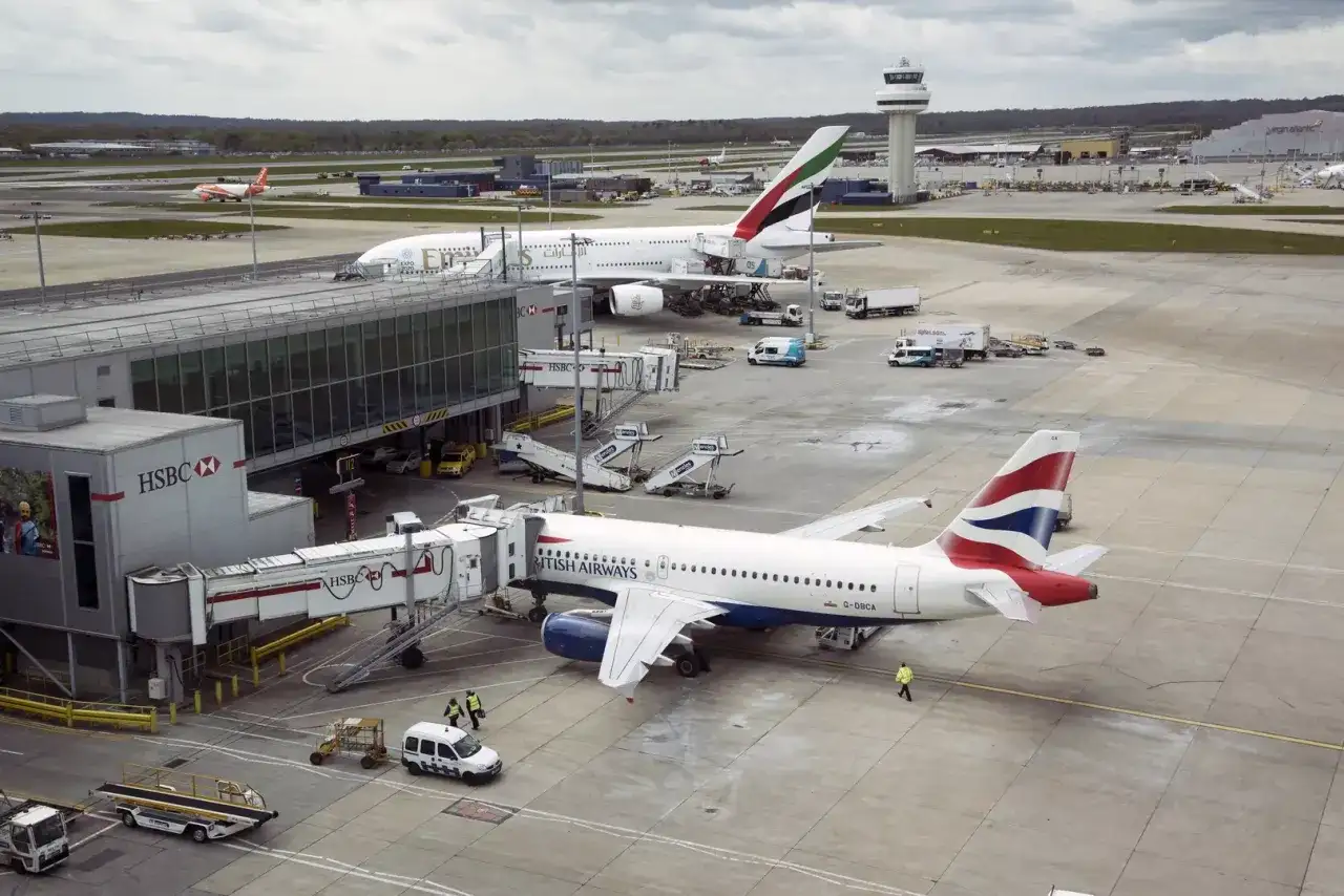 Port lotniczy Londyn Gatwick: samoloty British Airways i Emirates przy rękawach, w tle wieża kontroli lotów.