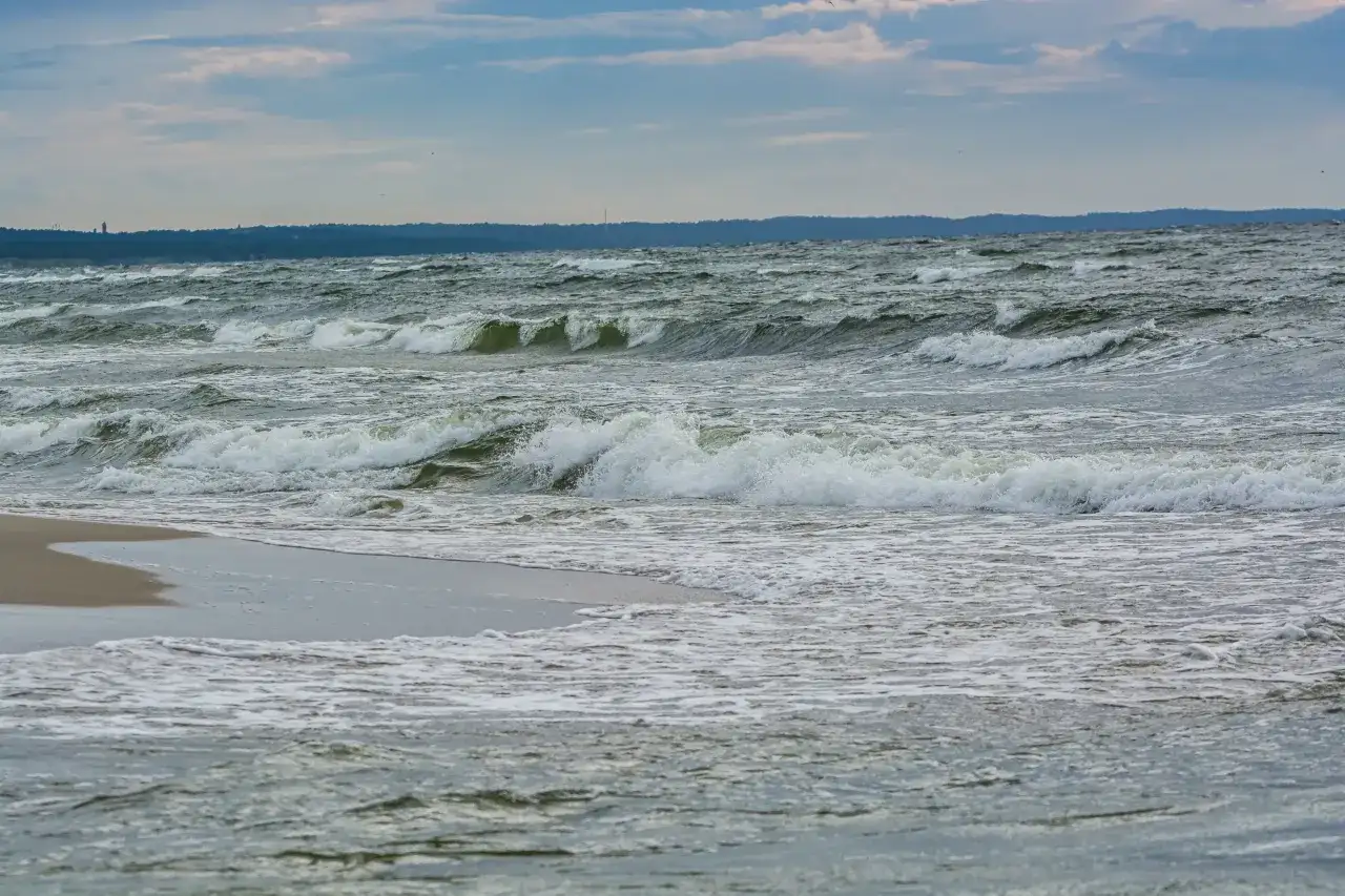Fale rozbijają się o brzeg. Zastanawiasz się, co robić zimą nad morzem? Spacer po plaży i podziwianie żywiołu to świetny pomysł.