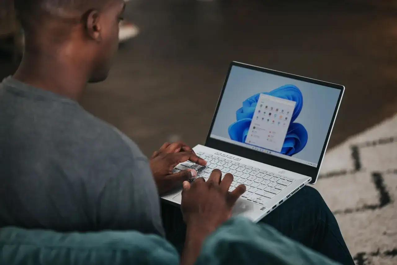 Mężczyzna na laptopie z systemem Windows 11, szukający informacji, jak zmienić nazwę użytkownika Windows 11.