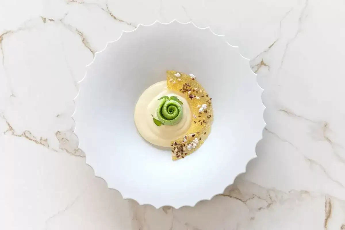 Dessert crémeux avec spirale verte, garni de fruits confits et graines.