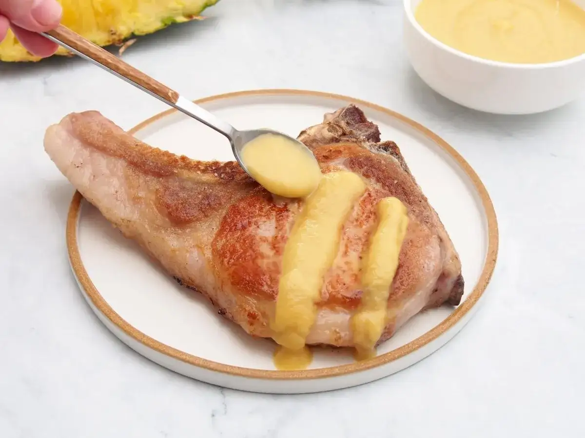 Chuleta de cerdo servida con una deliciosa salsa de piña, que realza su sabor.