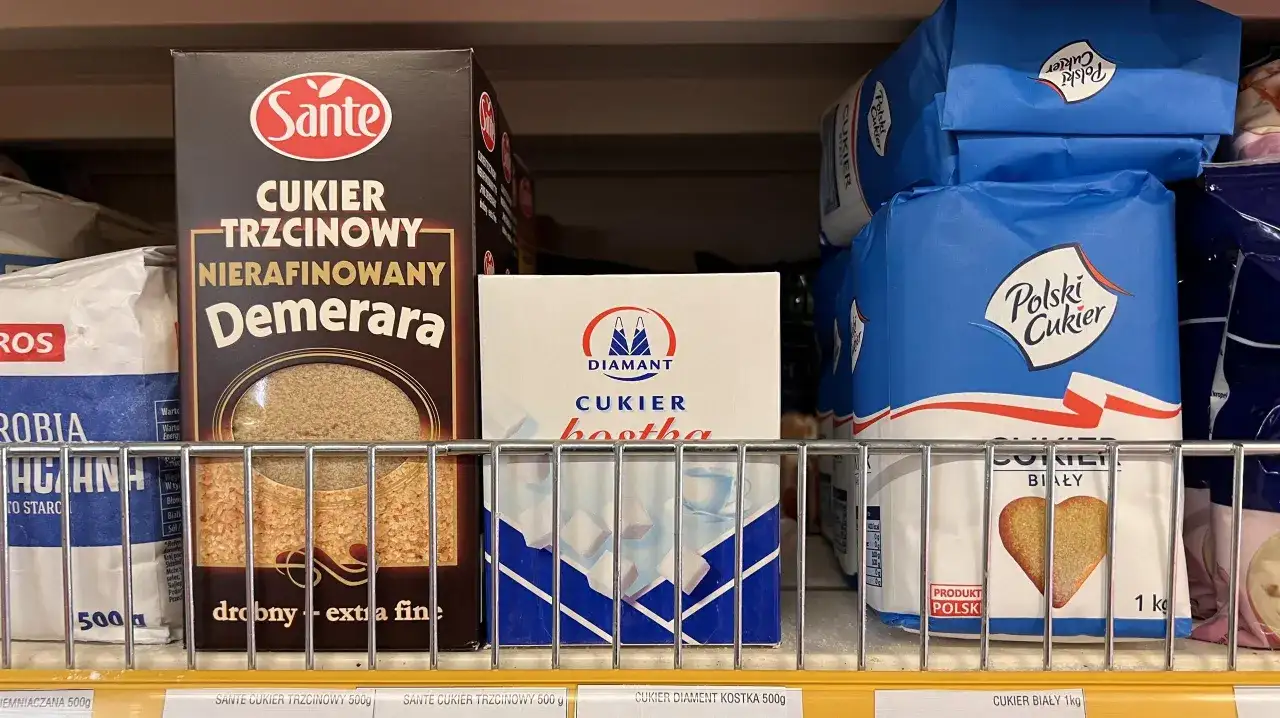 Półka sklepowa z różnymi rodzajami cukru: trzcinowym, białym w kostkach i w kryształkach.