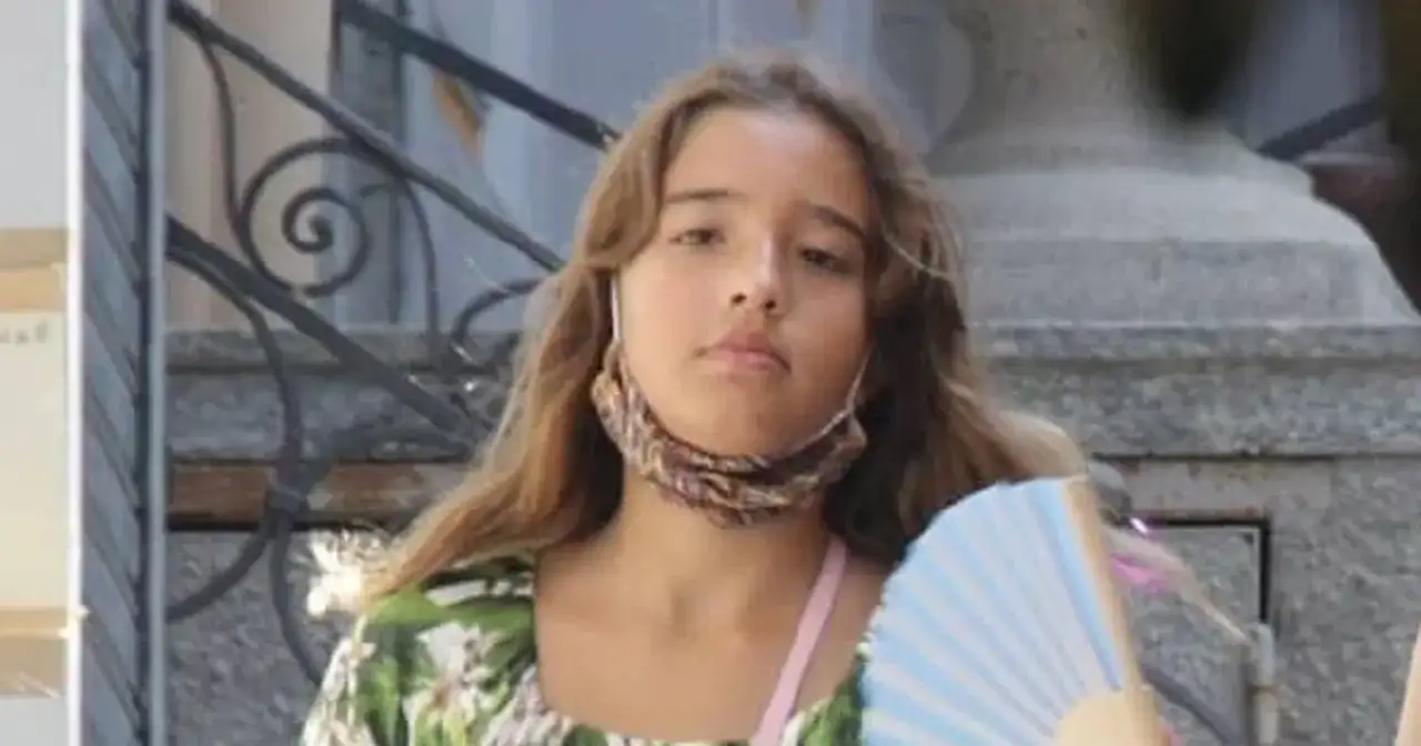 Léonie Cassel, z wachlarzem w ręku i maseczką na szyi, w kwiecistej sukience.