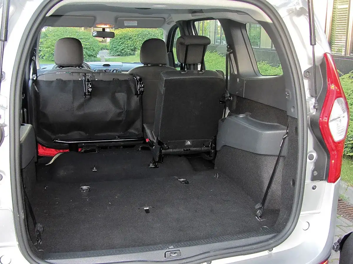 Pusta przestrzeń bagażnika Dacia Lodgy, gotowa na podróż. Widoczne złożone tylne siedzenia i siatka zabezpieczająca.