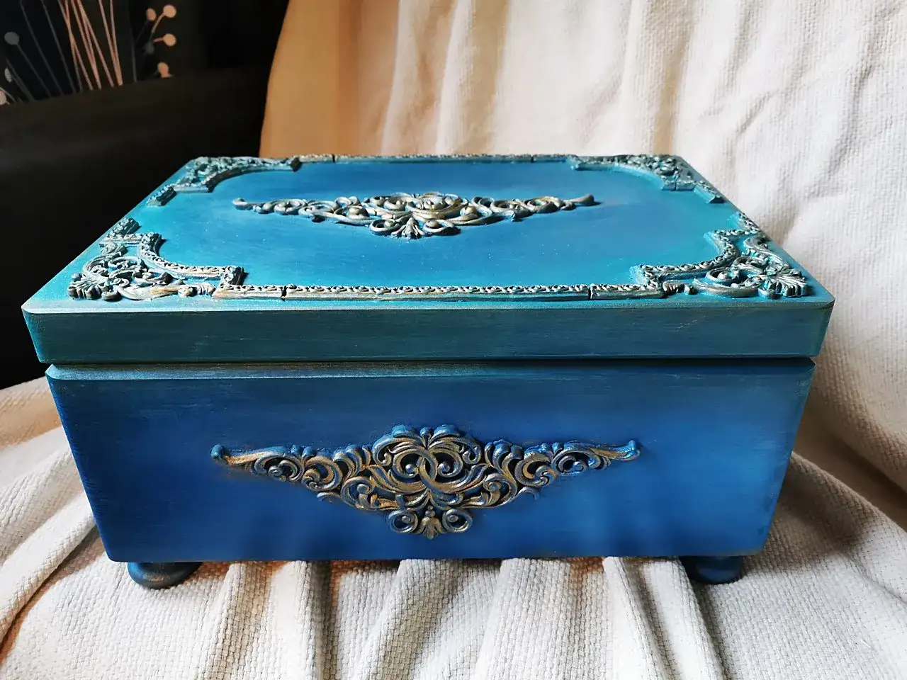 Elegancka, turkusowa skrzynia na skarby z ozdobnymi, złotymi ornamentami. Idealna do przechowywania cennych drobiazgów.